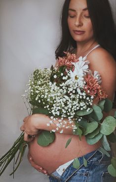 a pregnant woman holding flowers in her belly