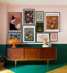 a room with posters on the wall and a dresser in front of it that has an orange lamp next to it