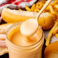 a person holding a wooden spoon over a jar filled with peanut butter and french fries