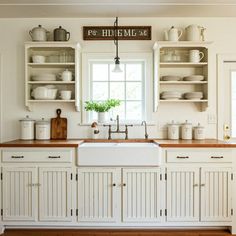 a white kitchen with wooden counter tops and open shelving above the sink is filled with dishes