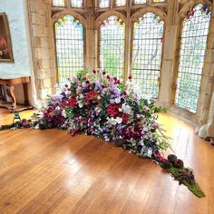 an arrangement of flowers is on the floor in front of two large stained glass windows