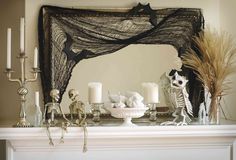 a mantel decorated with candles and skeleton figurines