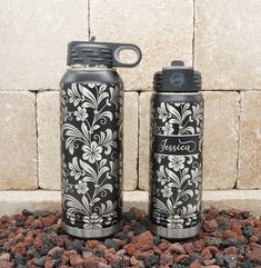 two black and white flasks sitting next to each other on some rocks near a brick wall