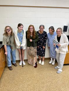 five women standing together in front of a wall