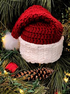 a red and white knitted hat sitting on top of a christmas tree