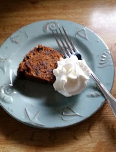 a piece of cake and whipped cream on a blue plate with a fork next to it