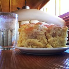 a piece of cake sitting on top of a white plate next to a glass filled with water