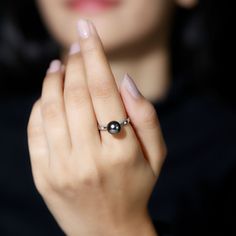 a woman wearing a ring with a black pearl on it