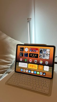 an open laptop computer sitting on top of a white table next to a lamp and pillows