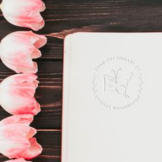 pink tulips next to an open book on a wooden table with the words from the library of gentle washington