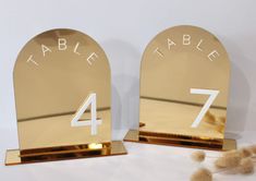 two gold table numbers are placed next to each other on top of some fluffy balls