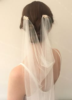 the back of a woman's head wearing a white veil with pearls on it