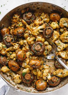 a pan filled with mushrooms and cauliflower on top of a white table cloth