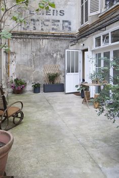 an outdoor patio with chairs and potted plants on the side of the building next to it