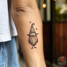 a small tattoo on the arm of a man with a gnome hat and crossbones