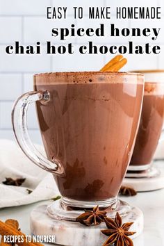 Photo of a glass mug filled with frothy hot chocolate sprinkled with ground cinnamon spices and garnished with a cinnamon stick sitting on a marble coaster, surrounded by a white kitchen towel, star anise pods and cinnamon sticks with another mug of hot chocolate in the background with text that says Easy to Make Homemade Spiced Honey Chai Hot Chocolate. Chai Homemade, Chai Hot Chocolate, Spiced Hot Chocolate Recipe, Healthy Hot Chocolate Recipe, Spiced Hot Chocolate