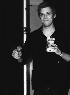 black and white photograph of a man holding a bottle in one hand and an object in the other