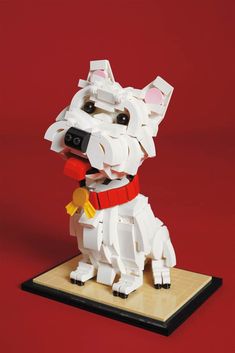 a dog made out of legos sitting on top of a wooden table next to a red wall