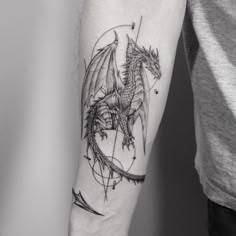 a black and white photo of a dragon tattoo on the left arm with an arrow