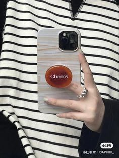 a woman holding up her phone case with the word cheers on it in front of her