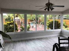 a living room filled with furniture and large windows overlooking a backyard area that's fenced in