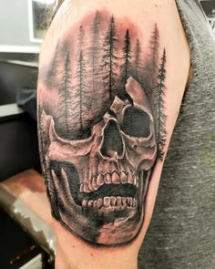 a man's arm with a skull and trees on it