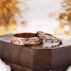 two gold wedding rings sitting on top of a wooden box in the middle of snow