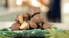 chocolates are stacked on top of each other in a green tray with pine needles