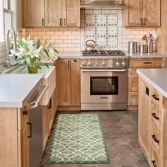 a kitchen with wooden cabinets and stainless steel stove top oven next to an area rug