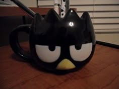 a black and white cat mug sitting on top of a wooden table