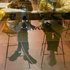 the reflection of two people sitting at a table in front of a glass window,