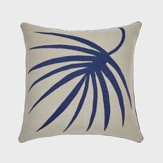 a blue and white pillow with a palm leaf design on it's front side