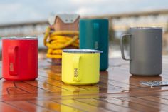 four different colored cups sitting on top of a wooden table