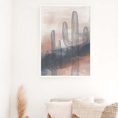 a painting hanging on the wall above a couch in a room with white walls and pillows