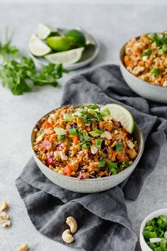 two bowls filled with rice and vegetables on top of a gray towel next to some lime wedges