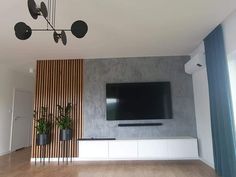 a living room with a flat screen tv on the wall and potted plants next to it