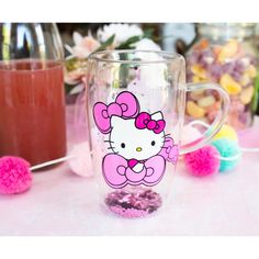 a hello kitty coffee mug sitting on top of a table next to some candies