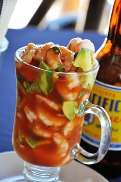 a glass filled with food next to a bottle