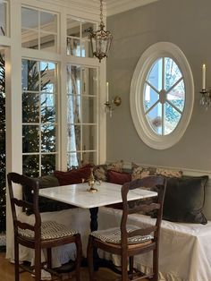 a table and chairs in front of a large window with a christmas tree behind it