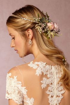 the back of a woman's head with flowers and leaves in her hair, wearing a wedding dress