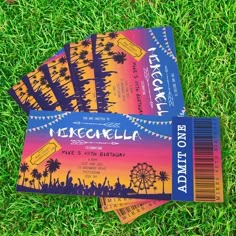 four tickets sitting on top of green grass in front of a ferris wheel and palm trees