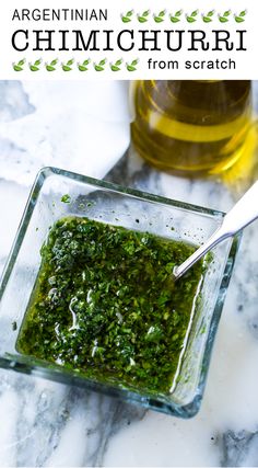 a glass bowl filled with green pest next to a bottle of olive oil and a spoon