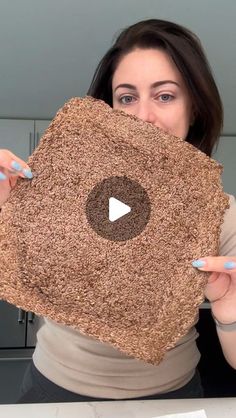 a woman holding up a square shaped rug