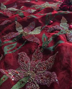 red and green embroidered fabric with flowers on the bottom, along with other material that has been sequined onto it