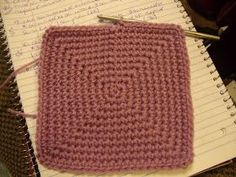 a crocheted square sitting on top of a notebook