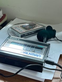 an electronic device sitting on top of a table next to some papers and headphones