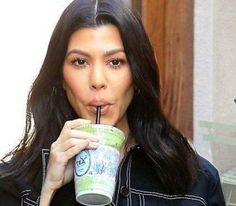 a woman with long dark hair drinking from a cup