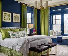 a bedroom with blue walls, green curtains and a white bed in the center surrounded by two windows