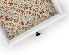 an open white box with floral wallpaper on it's sides and black handles