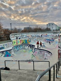 several skateboarders are at the top of a ramp in a skate park with graffiti on it